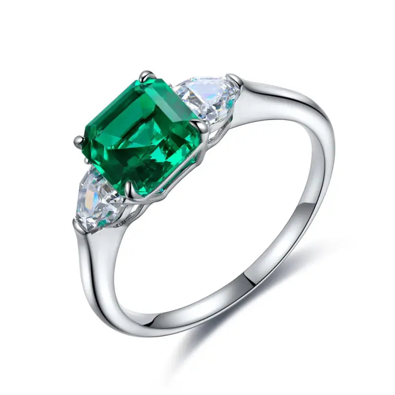 Silver ring featuring a square-cut emerald gemstone flanked by two smaller clear stones.