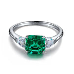 Load image into Gallery viewer, Silver ring featuring a square-cut emerald gemstone flanked by two smaller diamonds.
