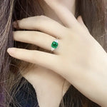 Load image into Gallery viewer, Emerald ring with a square-cut green gemstone and diamond accents on a pale hand.
