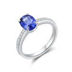 Load image into Gallery viewer, Silver ring featuring a vibrant blue oval gemstone surrounded by small diamonds on the band.
