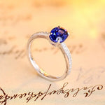 Load image into Gallery viewer, Silver ring with a round blue gemstone and small diamonds on the band.
