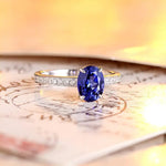 Load image into Gallery viewer, Elegant ring featuring an oval blue sapphire center stone flanked by small diamonds on a gold band.
