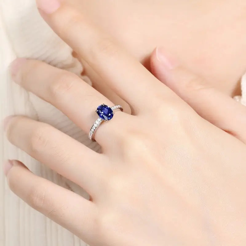 Sapphire and diamond engagement ring on a finger.