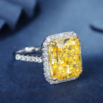 Load image into Gallery viewer, Dazzling yellow diamond ring with a halo of white diamonds set in a silver-toned band.
