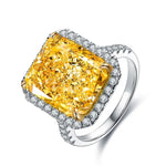 Load image into Gallery viewer, Dazzling yellow diamond ring with a halo of smaller white diamonds set in a silver-toned band.
