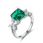 Load image into Gallery viewer, Silver ring featuring a square-cut emerald gemstone flanked by diamond accents.
