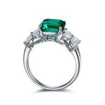 Load image into Gallery viewer, Emerald-cut green gemstone ring with diamond accents set in white metal.
