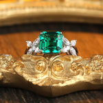 Load image into Gallery viewer, Emerald-cut green gemstone ring with diamond accents set in a precious metal band.
