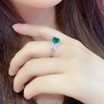 Load image into Gallery viewer, Ring featuring a vibrant emerald-cut green gemstone flanked by smaller clear stones.
