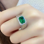 Load image into Gallery viewer, Emerald-cut green gemstone ring with diamond halo and split shank.
