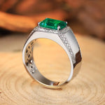 Load image into Gallery viewer, Silver ring featuring a prominent emerald-cut green gemstone surrounded by small diamonds.
