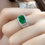 Load image into Gallery viewer, Emerald-cut green gemstone ring with diamond halo and band.
