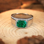 Load image into Gallery viewer, Emerald-cut green gemstone ring with diamond accents set in a wide silver band.
