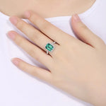 Load image into Gallery viewer, Emerald-cut green gemstone ring with diamond accents on a gold band.
