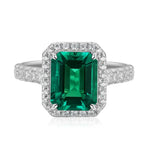 Load image into Gallery viewer, Emerald-cut green gemstone ring with diamond halo and band.
