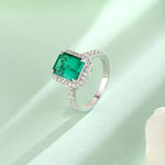 Load image into Gallery viewer, Emerald-cut green gemstone ring with diamond halo and band.
