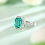 Load image into Gallery viewer, Emerald-cut gemstone ring with diamond halo and pavé band.
