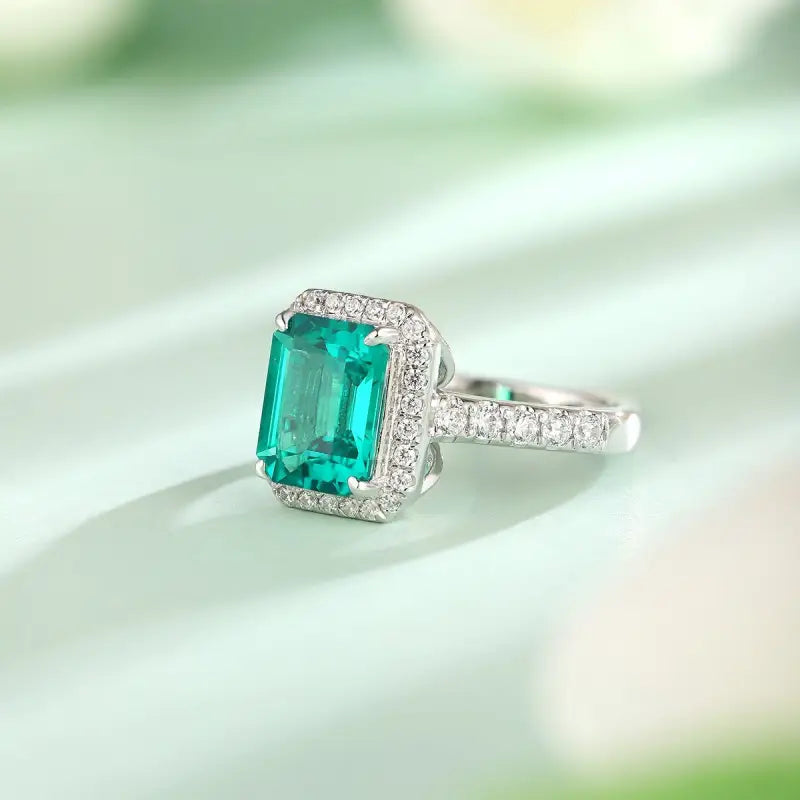 Emerald-cut gemstone ring with diamond halo and pavé band.