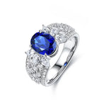 Load image into Gallery viewer, Ornate silver ring featuring a prominent oval blue sapphire surrounded by diamonds.
