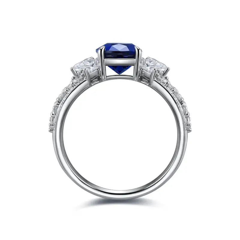 Elegant silver ring featuring a central blue gemstone flanked by smaller diamonds.