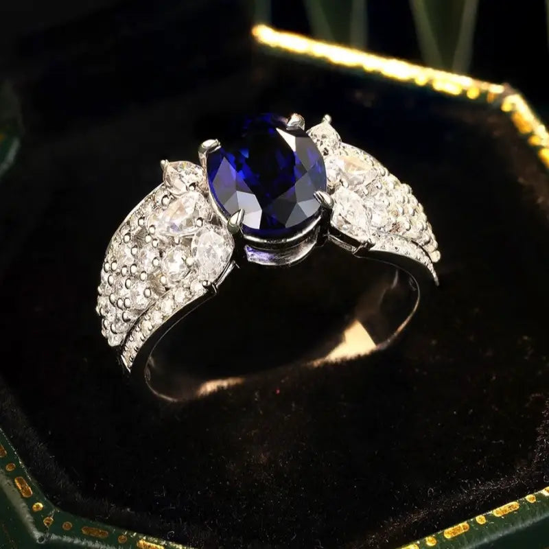 Elegant ring featuring a deep blue sapphire center stone flanked by diamond-encrusted bands.