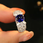 Load image into Gallery viewer, Ornate ring featuring a deep blue gemstone surrounded by diamonds.
