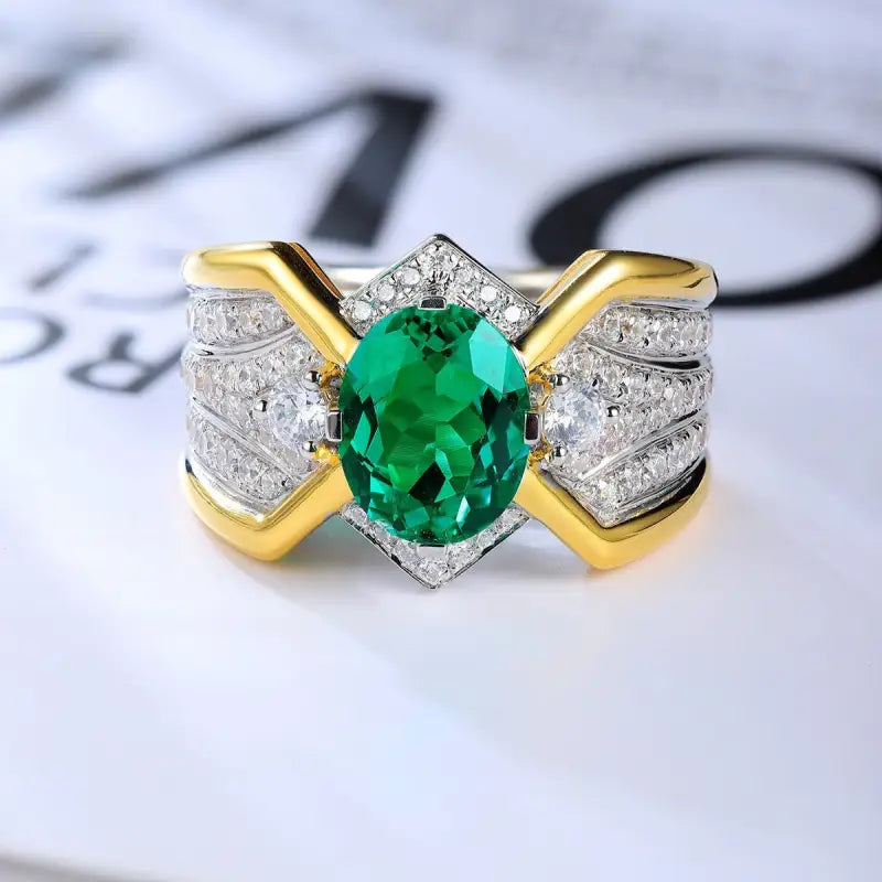 Ornate ring featuring a central oval emerald surrounded by diamonds in a gold and silver setting.