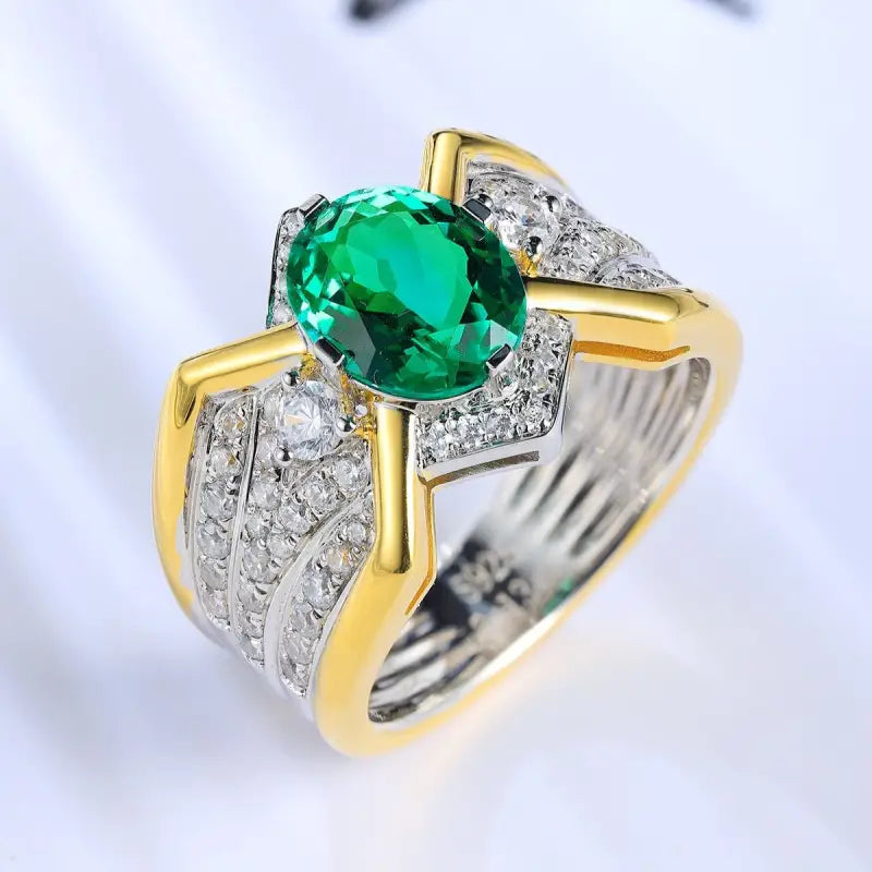 Ornate ring featuring a vibrant green gemstone surrounded by diamonds in a gold and silver setting.