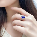 Load image into Gallery viewer, Sapphire ring with a halo of small diamonds on a woman’s finger.
