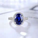 Load image into Gallery viewer, Oval-cut sapphire ring with diamond halo and band.
