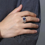 Load image into Gallery viewer, Silver ring with a dark blue gemstone worn on a person’s hand.
