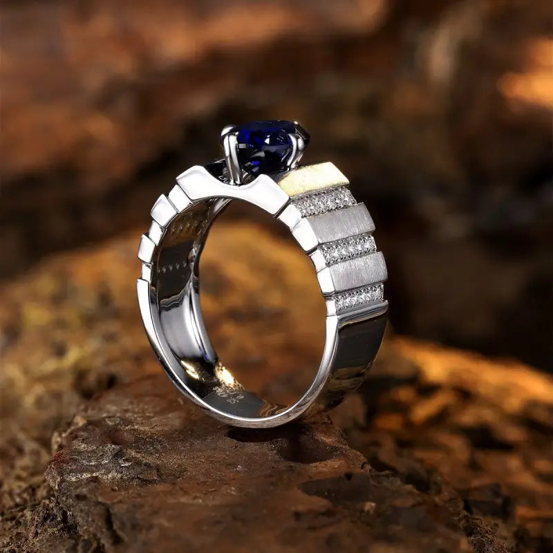 Silver ring with a deep blue gemstone and diamond accents on the band.