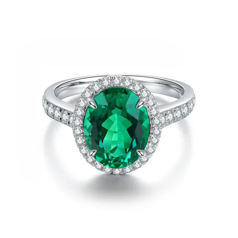 Oval emerald ring surrounded by diamonds in a white gold or platinum setting.