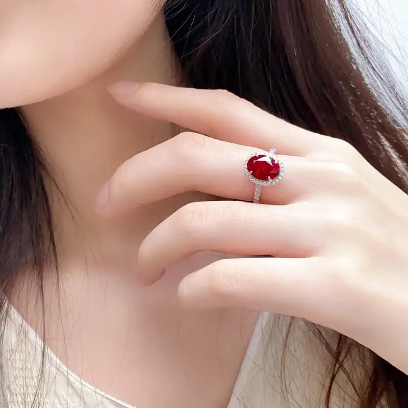 Ruby ring with a silver band on a person’s finger.