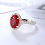 Load image into Gallery viewer, Oval-cut ruby ring with diamond halo and pave band.
