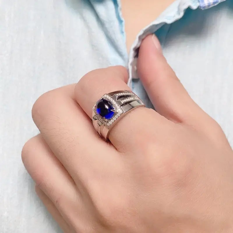 Ornate silver ring with a deep blue gemstone centerpiece.