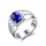 Load image into Gallery viewer, Silver ring with an oval blue sapphire surrounded by small diamonds.
