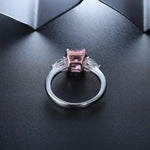 Load image into Gallery viewer, Silver ring with a square pink gemstone flanked by two smaller clear stones.
