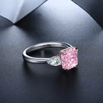 Load image into Gallery viewer, Engagement ring featuring a pink rectangular gemstone flanked by two smaller clear diamonds.
