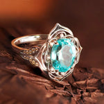 Load image into Gallery viewer, Ornate silver ring featuring a prominent oval-cut aquamarine gemstone surrounded by intricate metalwork.
