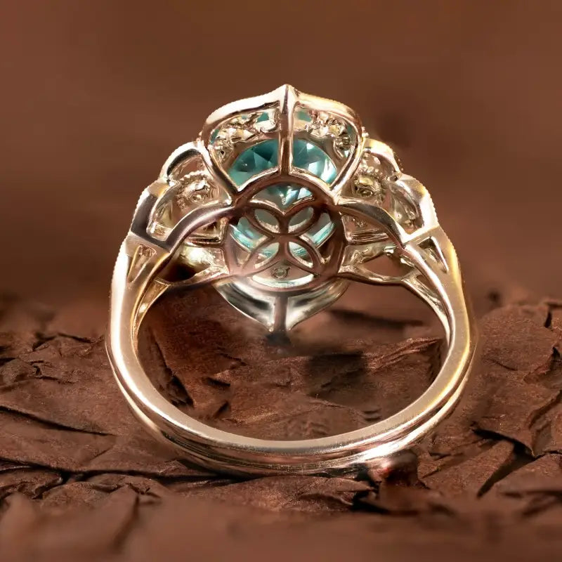 Ornate silver ring with a prominent blue-green gemstone in an intricate setting.