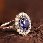 Load image into Gallery viewer, Ornate ring featuring a central blue gemstone surrounded by smaller diamonds.
