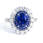 Load image into Gallery viewer, Ornate ring featuring a deep blue oval sapphire surrounded by diamonds.
