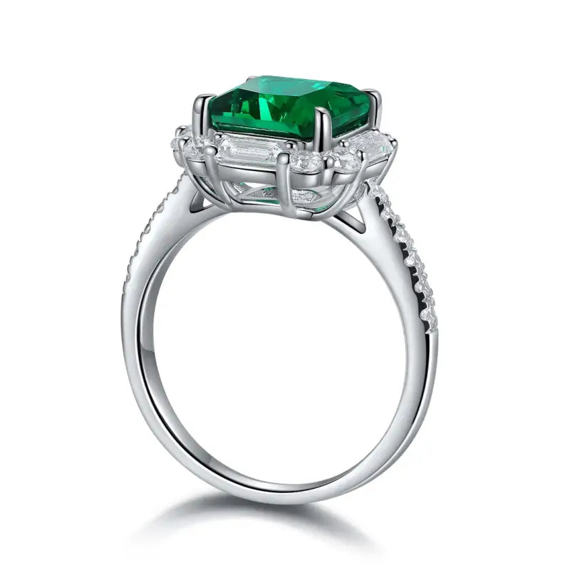 Silver ring featuring a square-cut emerald gemstone surrounded by smaller diamonds.