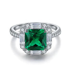 Load image into Gallery viewer, Emerald-cut green gemstone ring surrounded by diamonds in a white gold or platinum setting.
