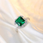 Load image into Gallery viewer, Emerald-cut green gemstone ring surrounded by smaller diamonds.
