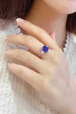 Load image into Gallery viewer, Ring with a vibrant blue gemstone set in a gold or silver band.
