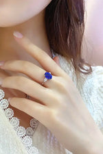 Load image into Gallery viewer, Ring with a vibrant blue gemstone on a person’s hand.
