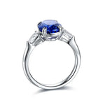 Load image into Gallery viewer, Silver ring featuring a deep blue oval gemstone flanked by smaller clear stones.
