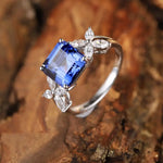 Load image into Gallery viewer, Elegant silver ring featuring a square-cut blue gemstone flanked by smaller white stones.
